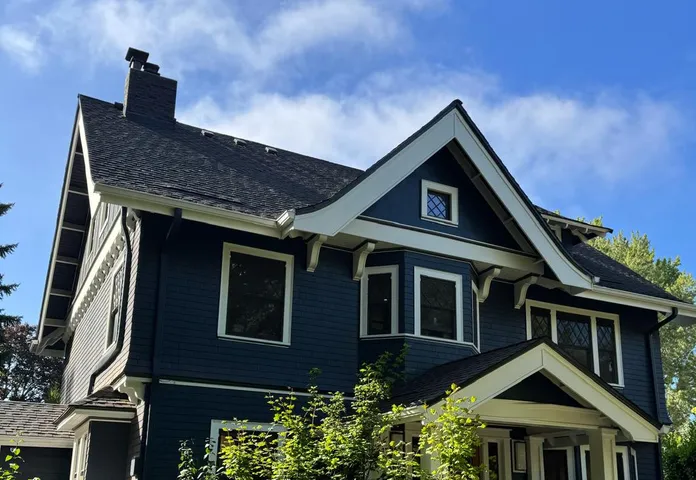Navy blue craftsman house with white trim and a painted porch railing, an Olvera exterior job