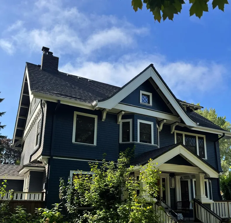 Navy blue craftsman house with white trim and a painted porch railing, an Olvera exterior job