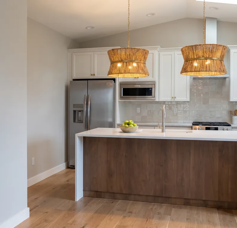 White shaker kitchen with rattan pendant lights and a walnut island