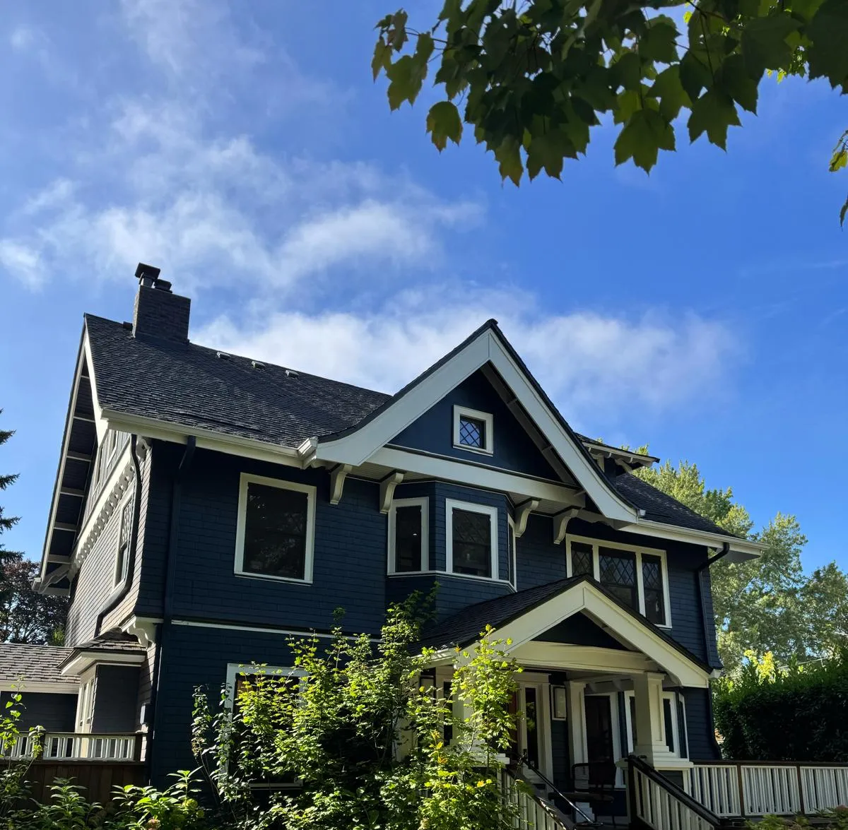 Navy blue craftsman house with white trim and porch railing, an exterior painted by Olvera Painting