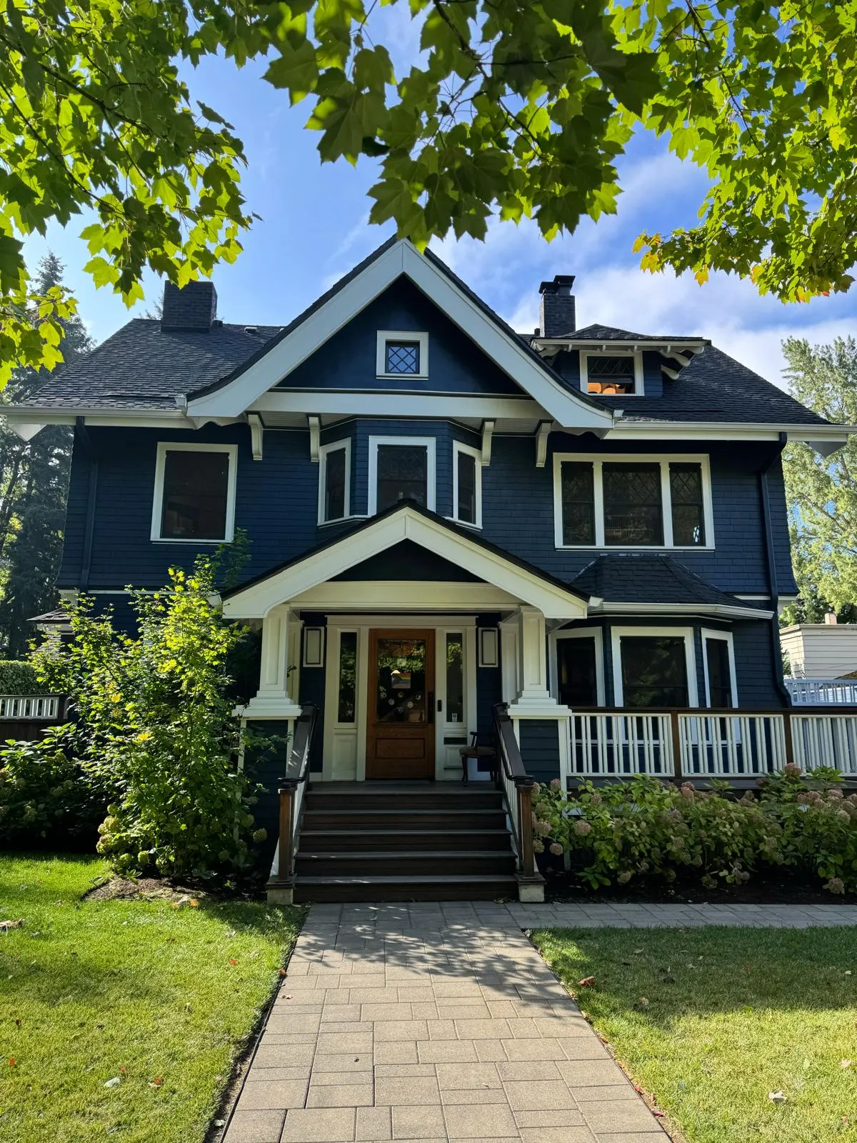 Front of a craftsman house painted navy blue with white trim, gable brackets and porch columns