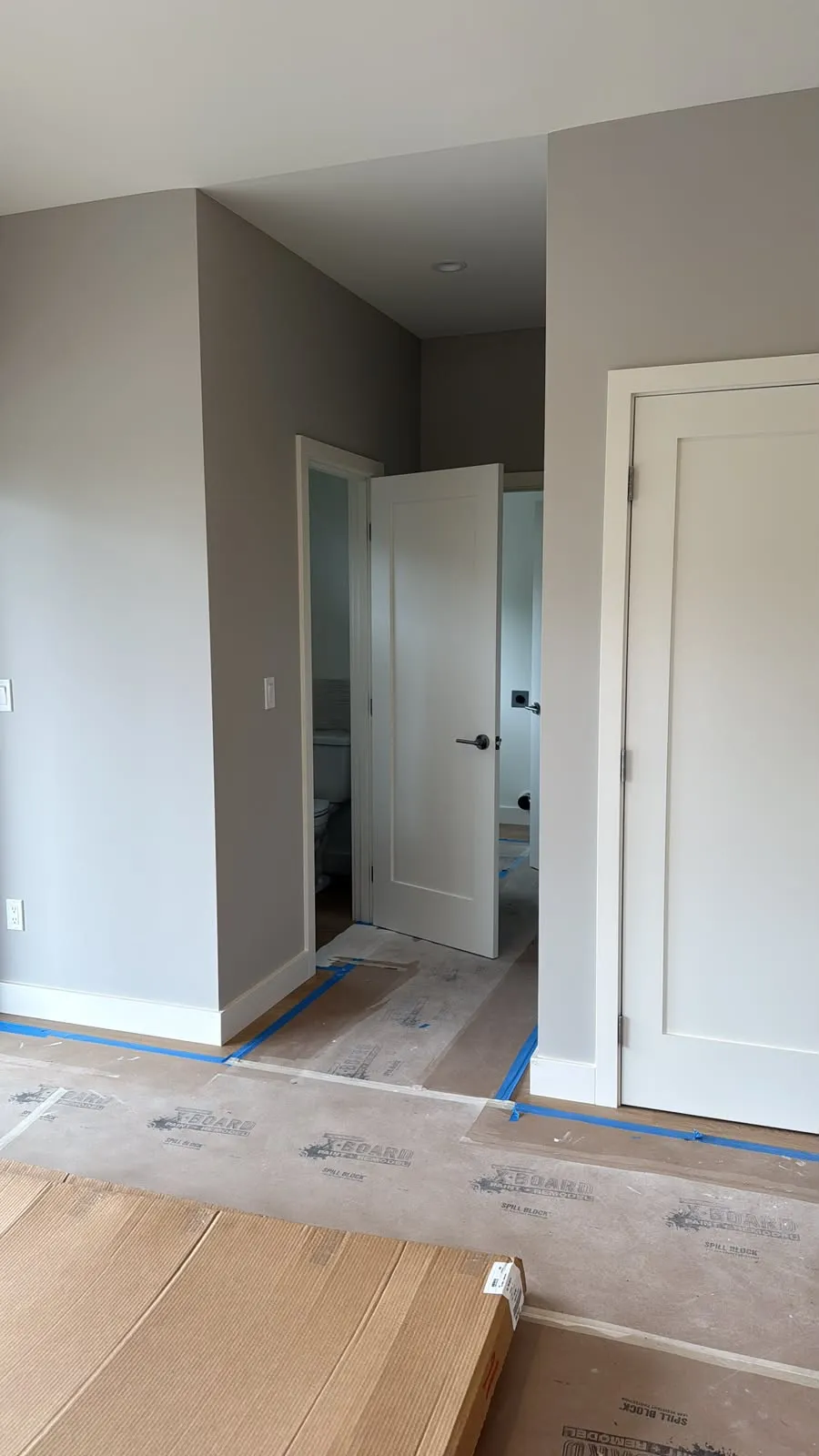 Gray walls and white doors with the floor covered and taped during the job