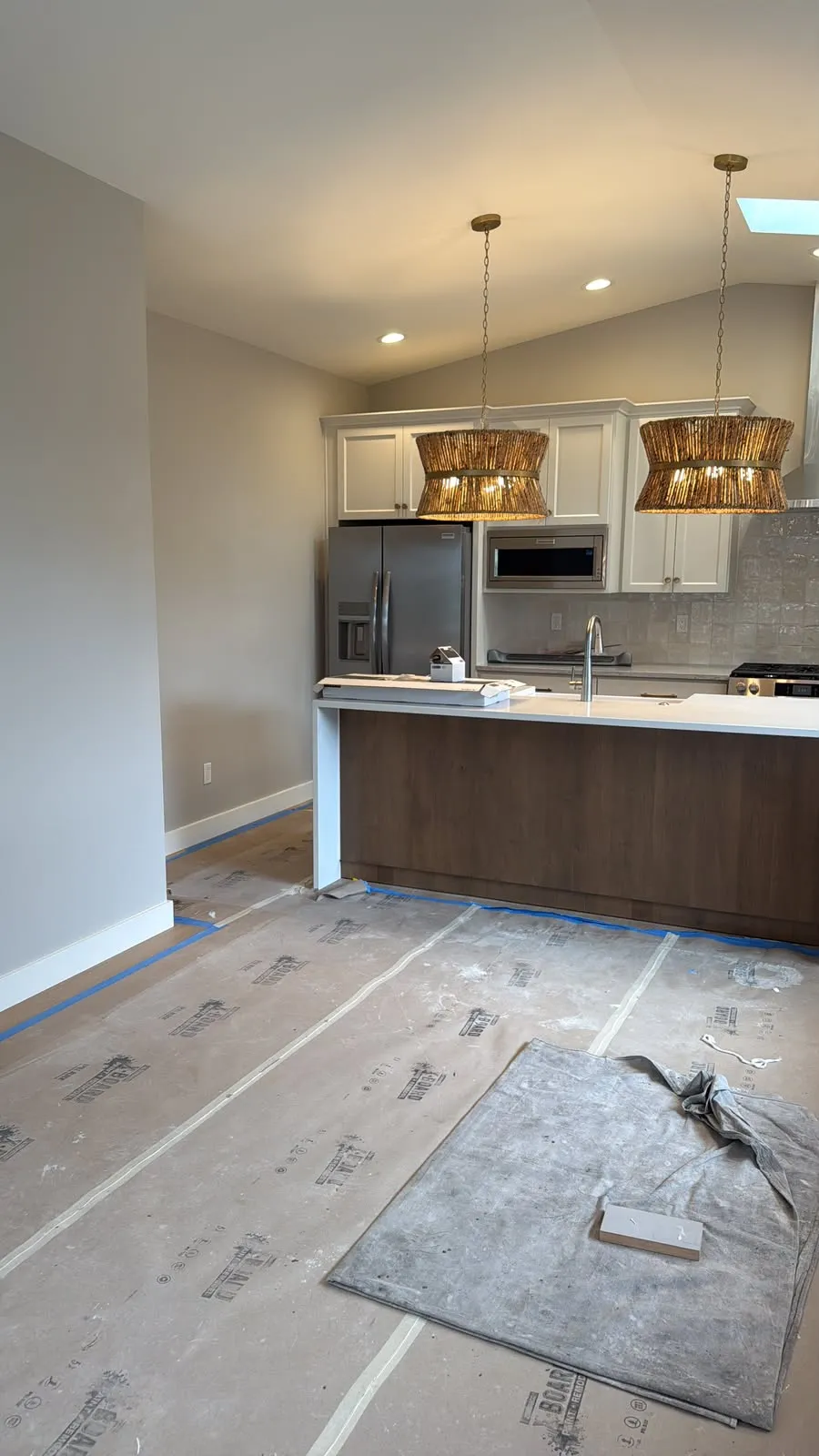 Kitchen with the floor covered in protective paper and blue tape along the edges
